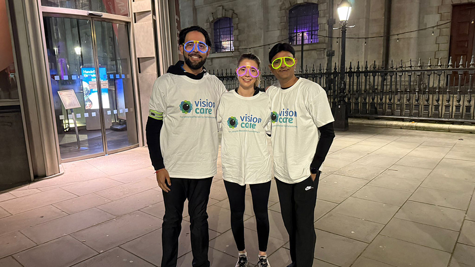 Three people stand together with the Vision Care t-shirts preparing for the London Walk
