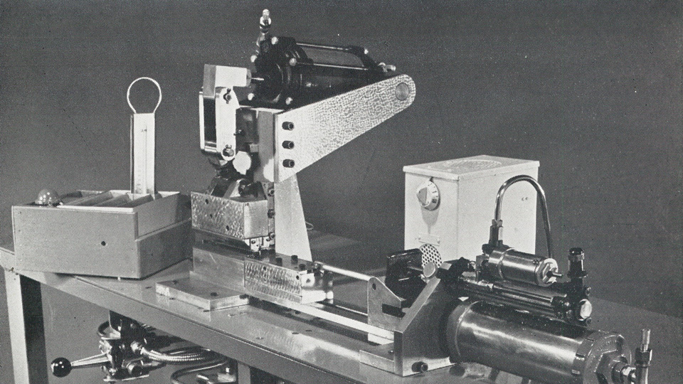 An old black and white photograph of a machine used to drive cores into the arms of frames for eyewear