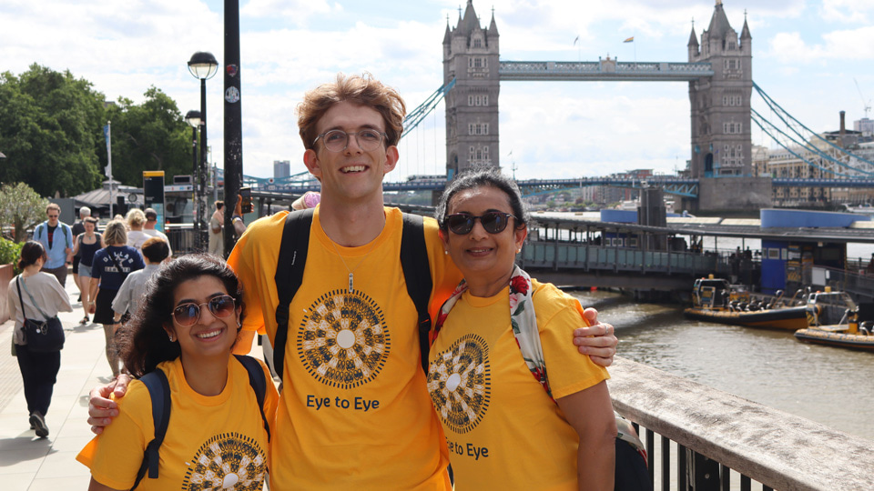 Three participants in yellow t-shirts smile in front of Tower Bridge