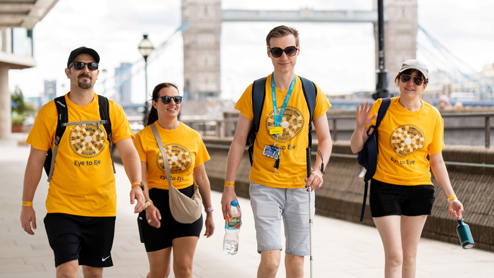 Four Eye to Eye participants in yellow t-shirts walk past Tower Bridge