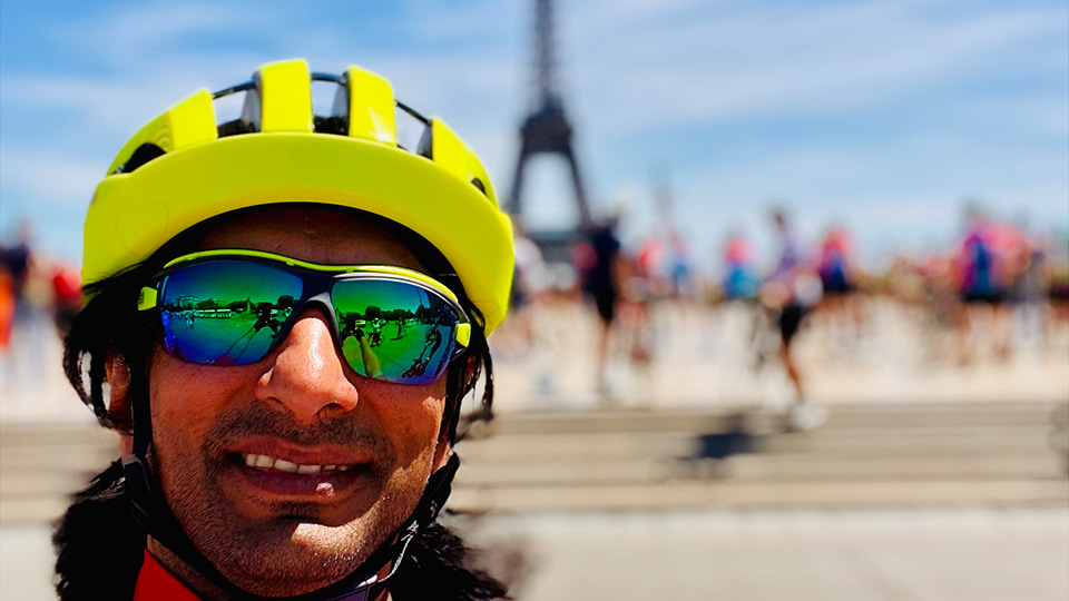 Vijay, helmetted and wearing polarised sunglasses, takes a selfie with the eiffel tower blurred in the background