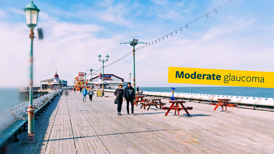 The same picture of a seaside pier but the far edges of the image have been blurred to indicate moderate glaucoma