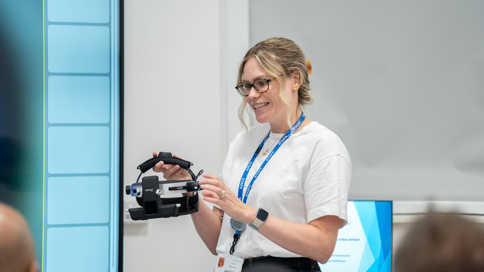 Rachel holds up a headset used for eye health measurements
