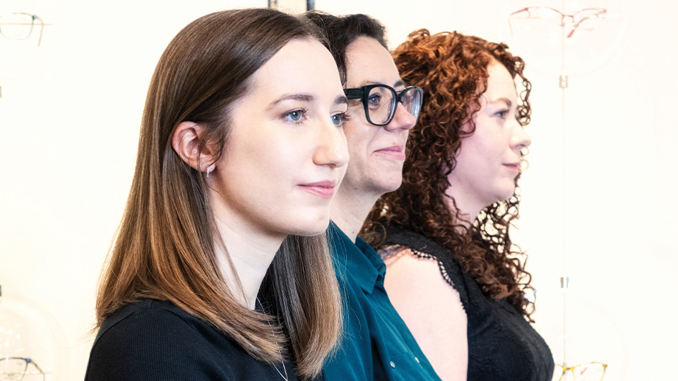 Mhairi Day, Stephanie Kearney and Emma Dow sit in a row smiling at the Glasgow Caledonian University Vision Centre  