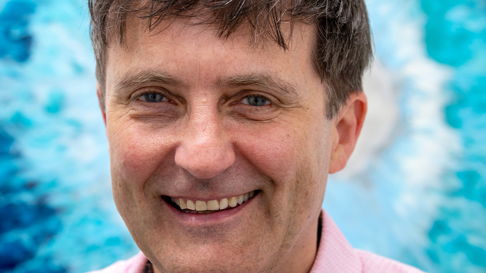 David Cummins is photographed in front of an iris artwork at the Anstruther branch of PLM Optometris