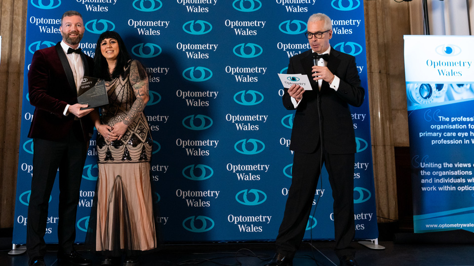 Sara receives the trophy for Practice Manager of the Year, wearing an art-deco inspired gold and black dress