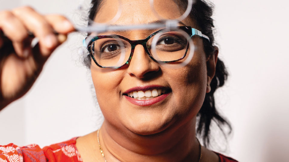 IP optometrist Bhavina Patel holds a pair of spectacles in front of her face 