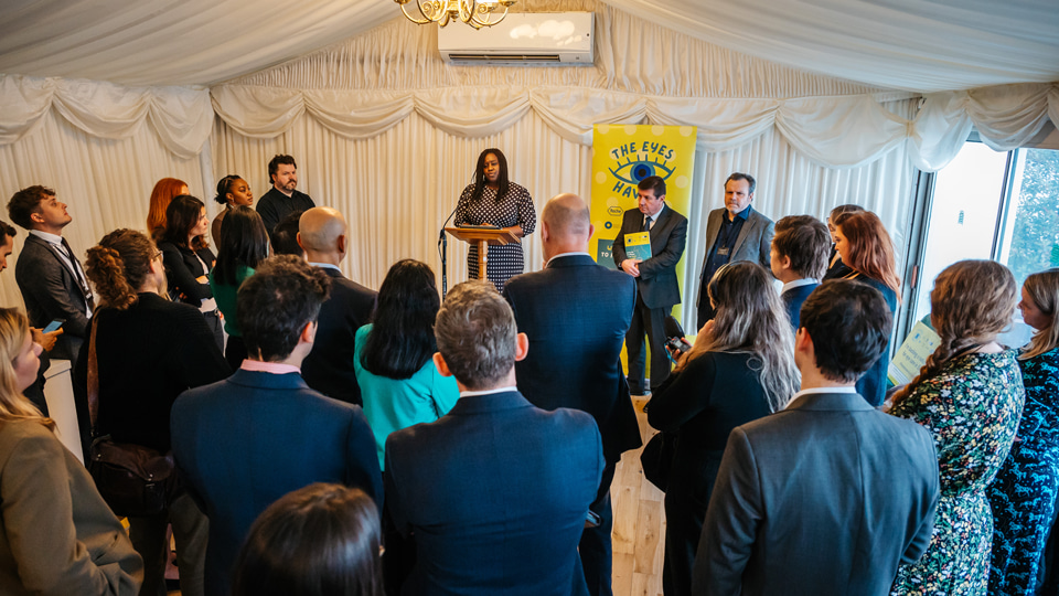 A crowd of people listening to woman speak 