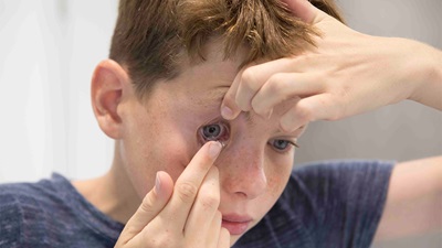 A boy putting in contact lenses