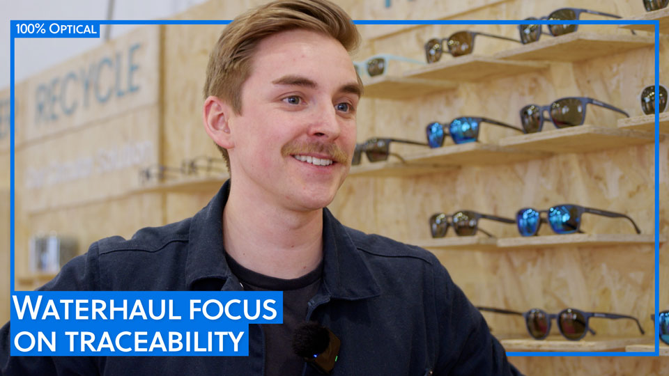 Kieran smiles from the Waterhaul stand, which is made of wood, at 100% Optical
