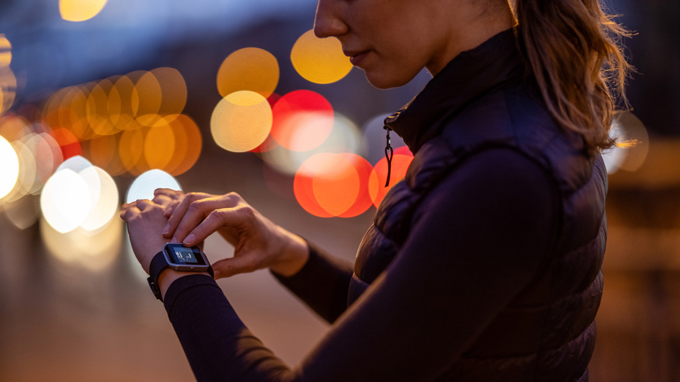 A woman wearing exercise clothes checks her smartwatch