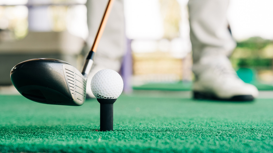 A close up of a person holding a golf club next to a golf ball