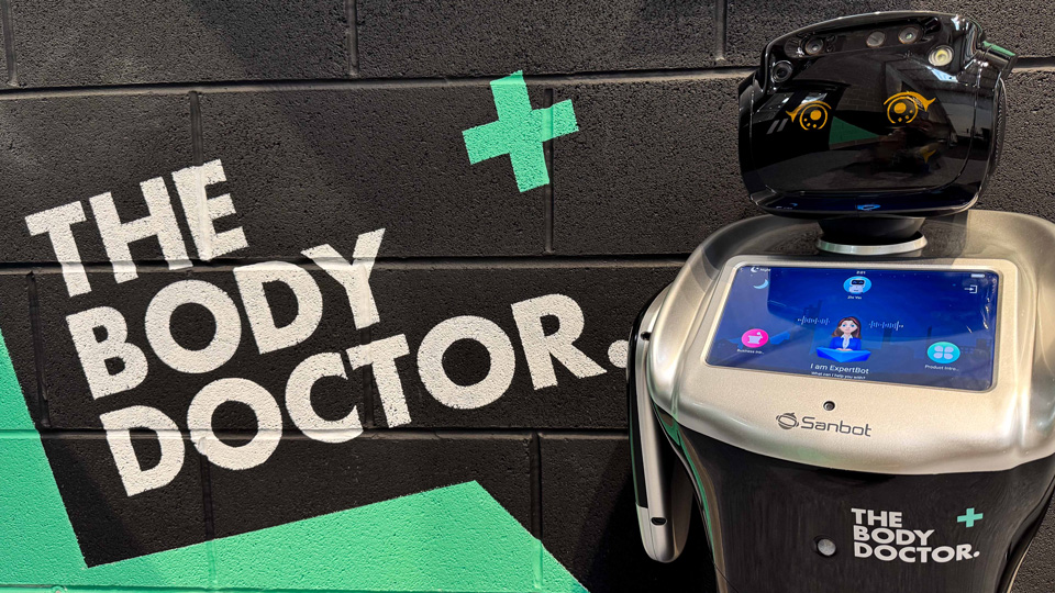 A friendly robot is positioned next to a logo for The Body Doctor