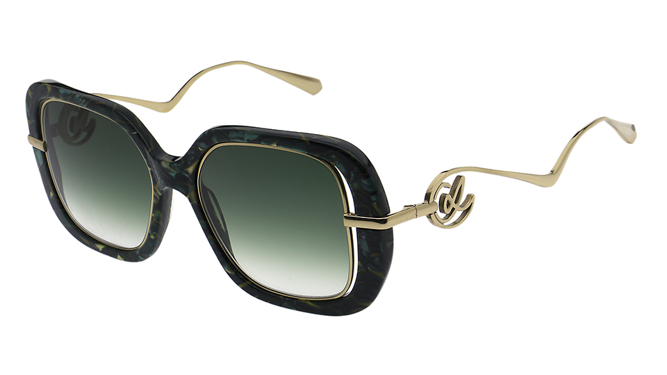 A pair of sunglasses with a thick marbled green frame front and wavy gold metal arms
