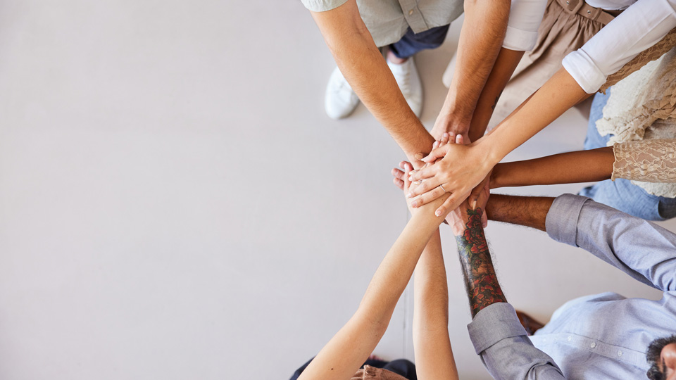 High angle view of a diverse group of people standing in a huddle with their hands together