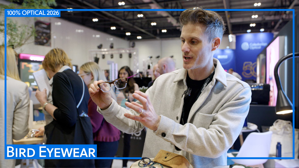 On the Bird Eyewear stall at 100% Optical, Ed Bird holds up one of the latest frames from the collection – it features a dark brow line, clear bottom half of the frame and vibrant pink metallic sides