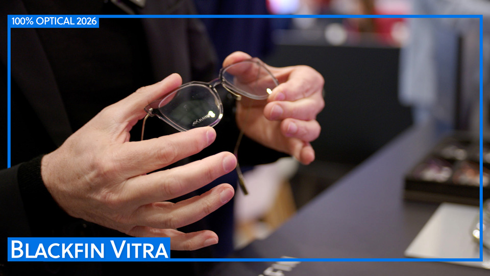 A close-up of hands holding a pair of spectacles made with a clear polymer frame front and thin titanium sides