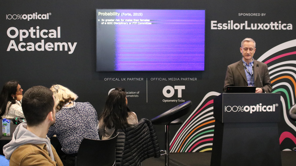 Bruce Evans is presenting, stood behind a lectuern, in front of a screen