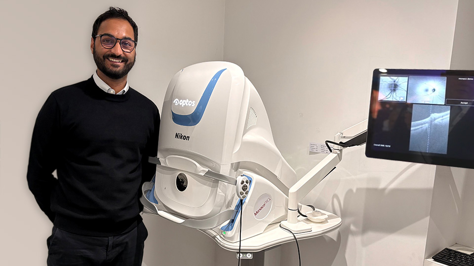 Vikesh stands smiling in his consulting room with his MonacoPro next to him 