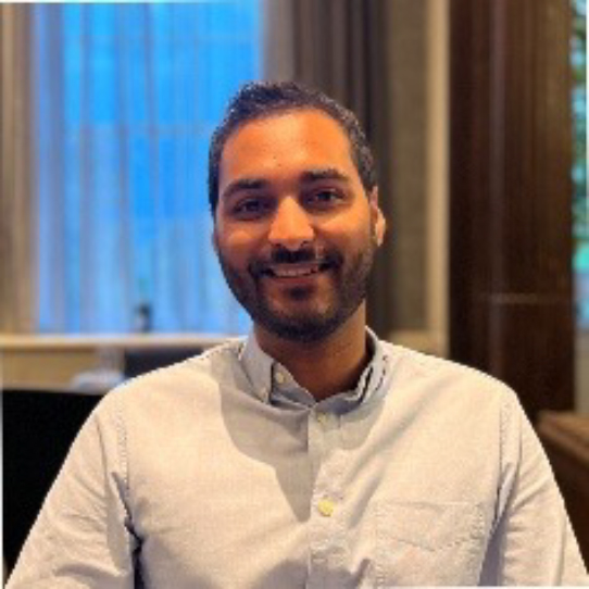Vikesh Chauan, lead optometrist at Edmonds & Slatter Opticians, smiling in a cream shirt 