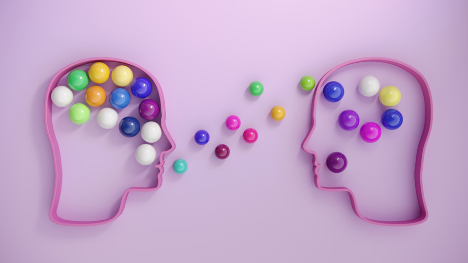 Human heads on a light purple background alongside lots of multi coloured spheres, symbolising communication concepts 