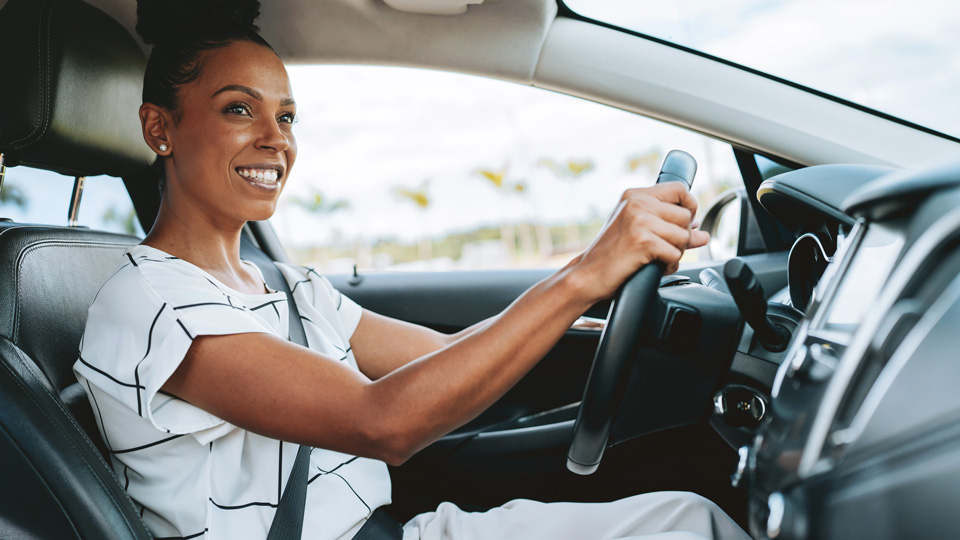 A professional smiling woman drives a car