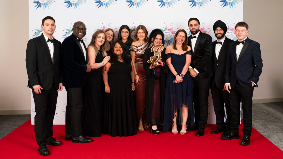 A group wearing black tie gather around an award – presented as a huge golden ‘B’. They stand on a red carpet and the mood is celebratory