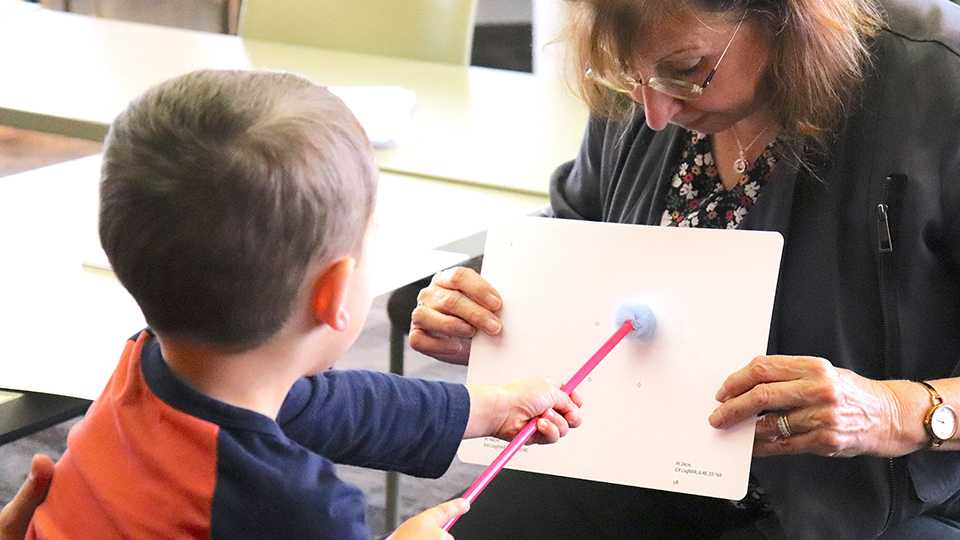 A child uses a pointer to indicate an image on the Waterloo Differential Acuity Test held by Professor Susan Leat