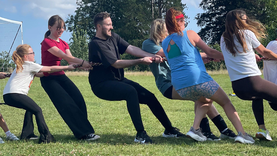 A group of people play tug of war outside