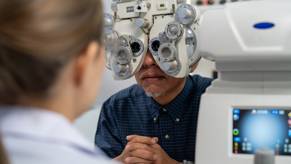 Optometrist adjusting phoropter during eye examination