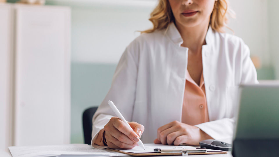 A medical professional fills out paperwork at her desk