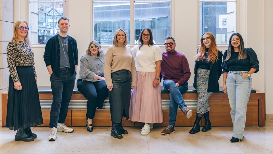 The practice team at Jones and Co are stood in a line inside a room, all smiling 