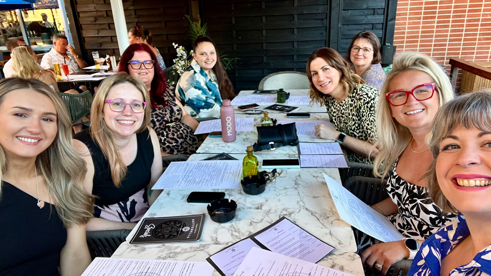 A group of women are seated at a long restaurant table