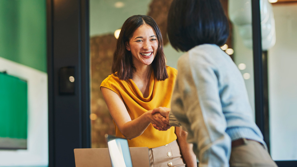  Two women in smart casual clothes shake hands