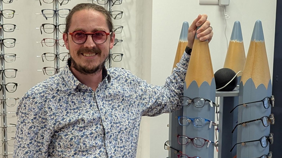 Jamie is stood next to children’s frames displayed on a giant pencil 
