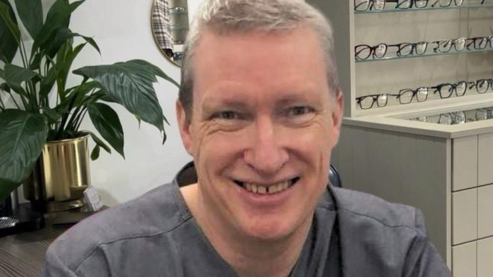 Dave wears grey scrubs and is photographed in the practice