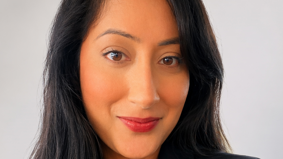 Jas smiles at the camera in a professional headshot