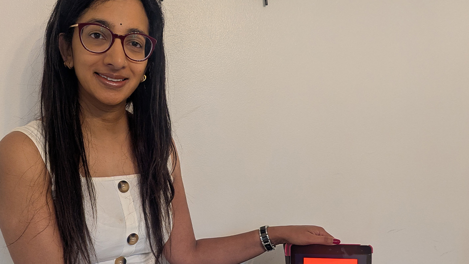 Sonia sits in a clinic with a piece of optical equipment
