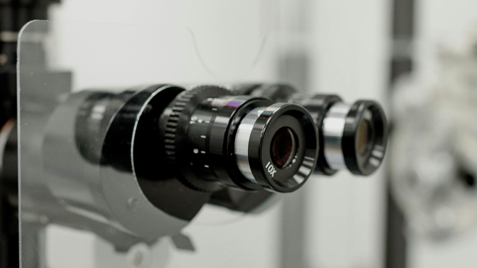 A close up of the viewing piece of a slit lamp device. A protective screen has also been fitted between the practitioner and patient