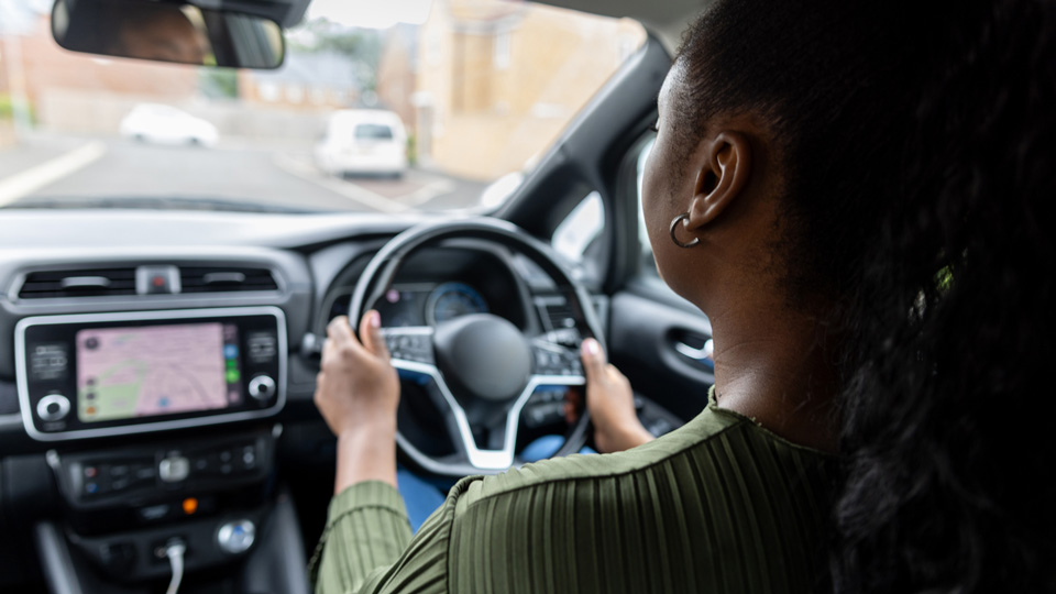 View over a woman’s shoulder as she drives an electric car