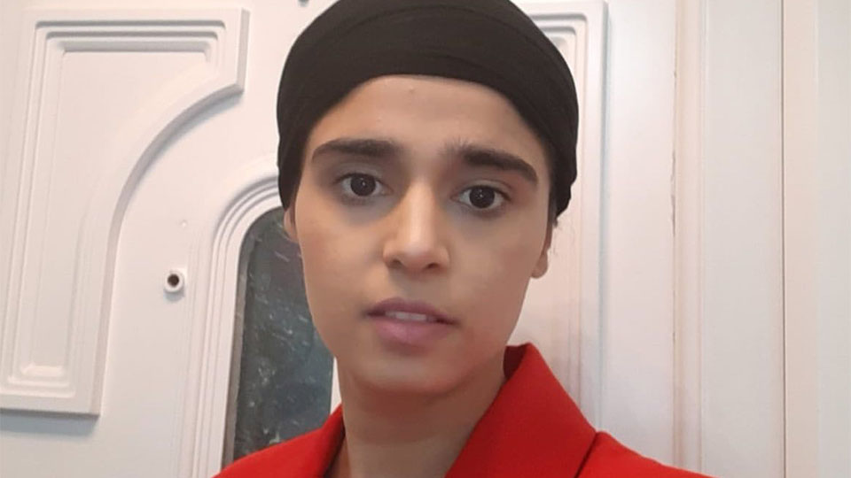 Head and shoulders shot of Jagdeep Kaur in a red suit in front of a door