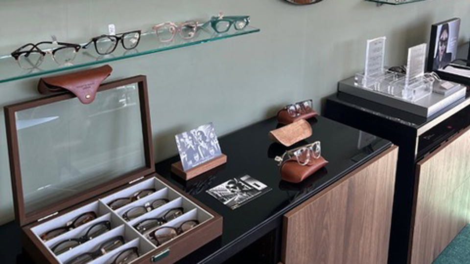 A wall of an optical practice with shelves of eyewear and a large circle mirror