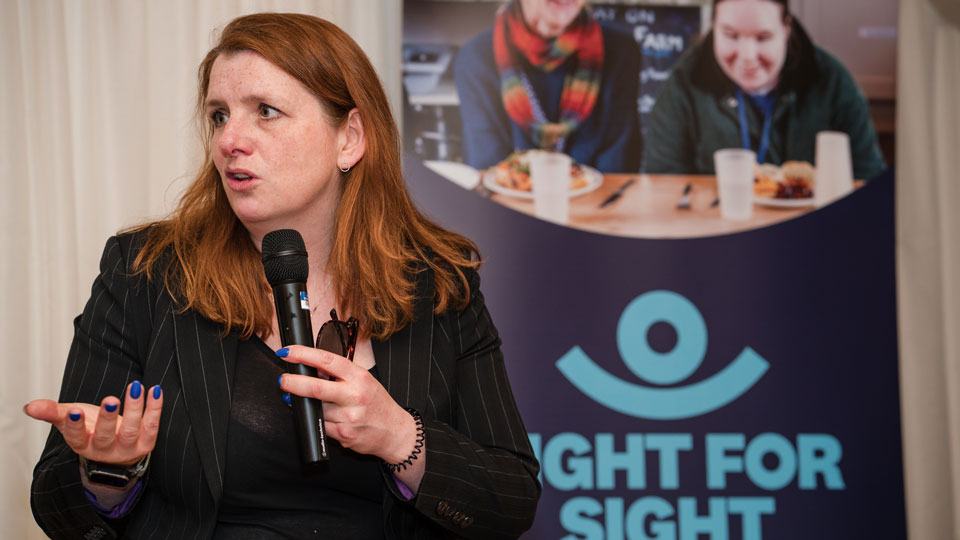Alison McGovern holds a microphone whilst speaking on a panel