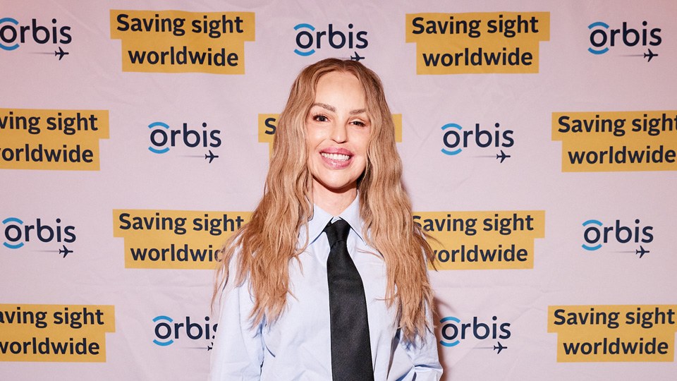 Katie Piper poses in front of a banner for Orbis