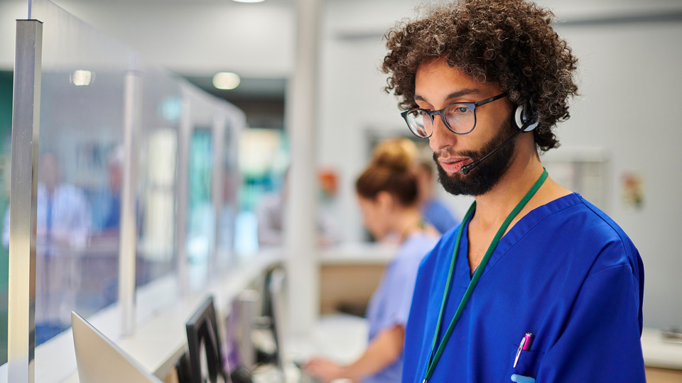 Hospital medical switchboard operator in blue scrubs 