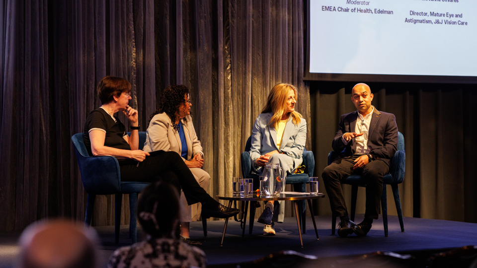 A panel of four people, three woman and a man, are seated on stage and in conversation