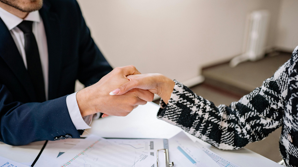 A handshake, focused on the two arms both in business attire