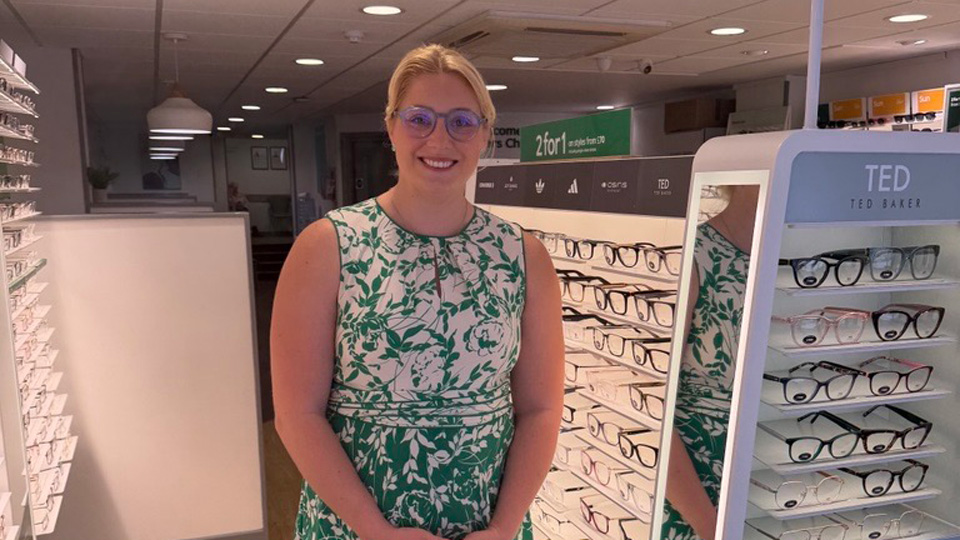 Emily Head smiles whilst stood on the practice floor in a green dress