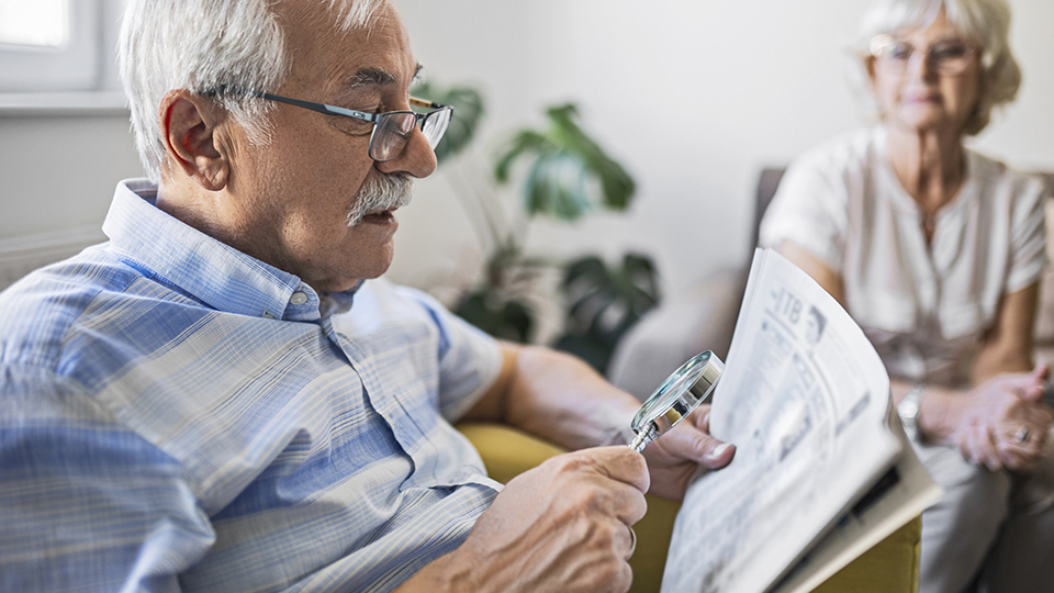 Senior man holding an magnifying glass he uses to help him read