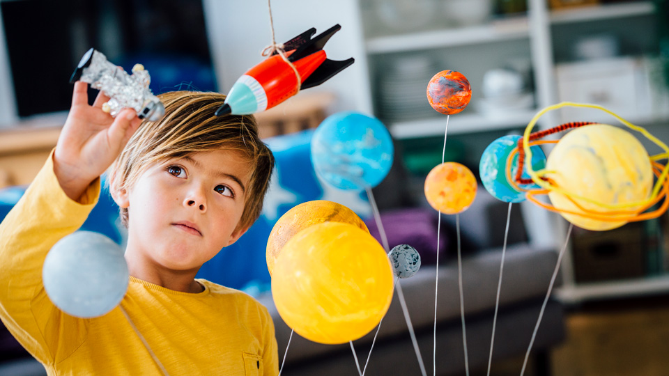 A child plays with a toy astronaut and rocket